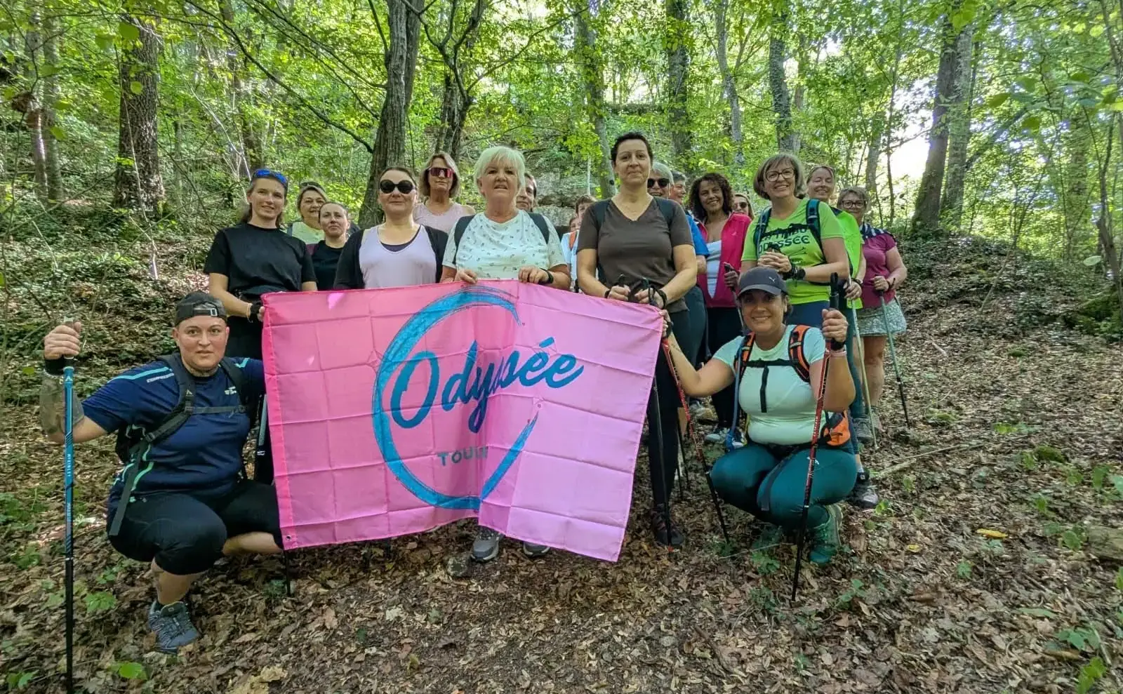Le groupe posant derrière la banderole rose de l’Odyssée, en sous-bois.