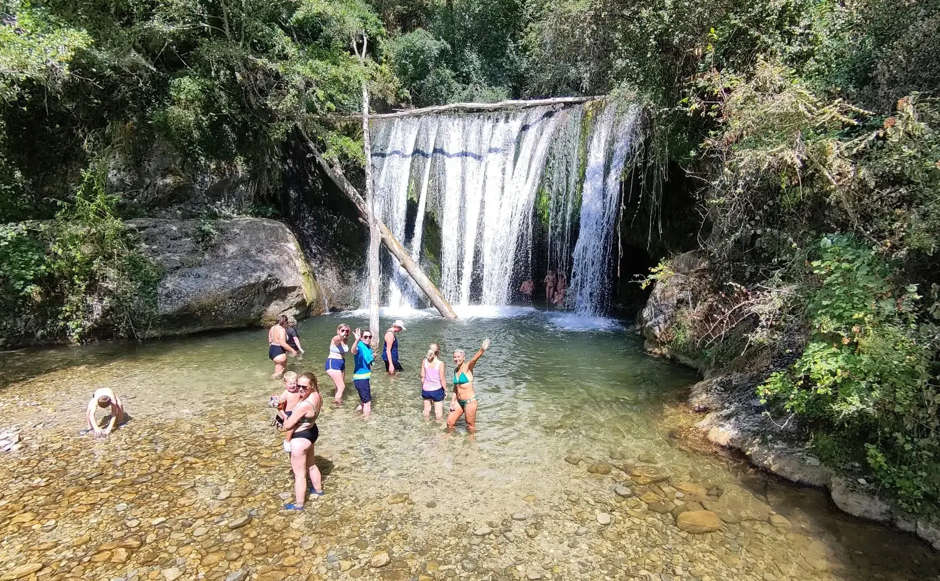 Une dizaine de membres de l’association se baignent dans la vasque au pied d’une cascade.