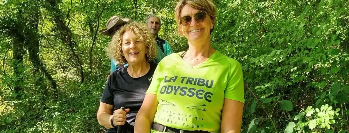 Deux marcheuses en chasuble « La Tribu Odyssée », bâtons en main, sur un sentier.