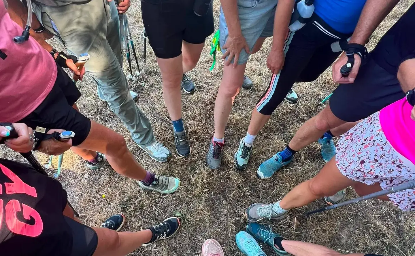 Vue du dessus : les marcheurs de l’association forment une ronde, chaussures et bâtons au centre.