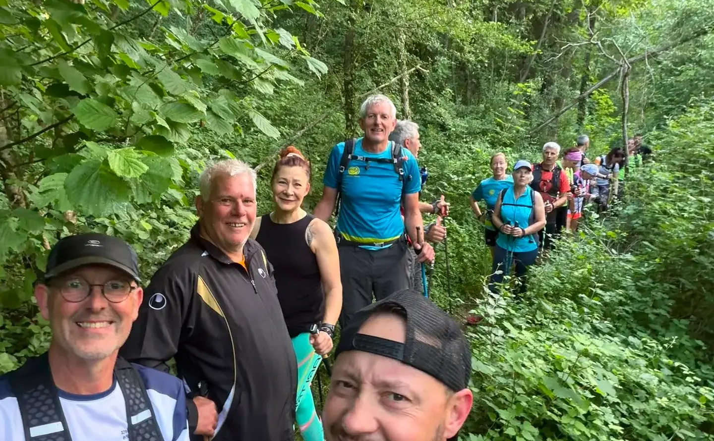 Sourires au premier plan, le groupe de l’association derrière, sur un sentier de sous-bois.